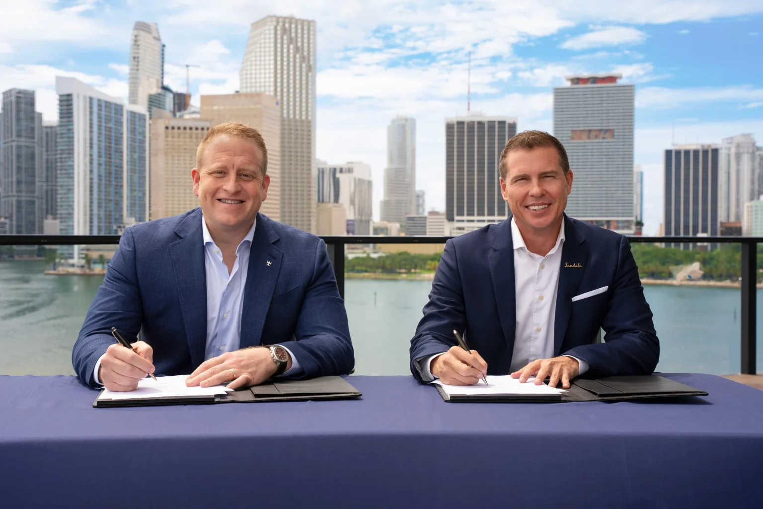 Jason Liberty and Adam Stewart sign the Royal Caribbean Group and Sandals Resorts partnership agreement in Miami.